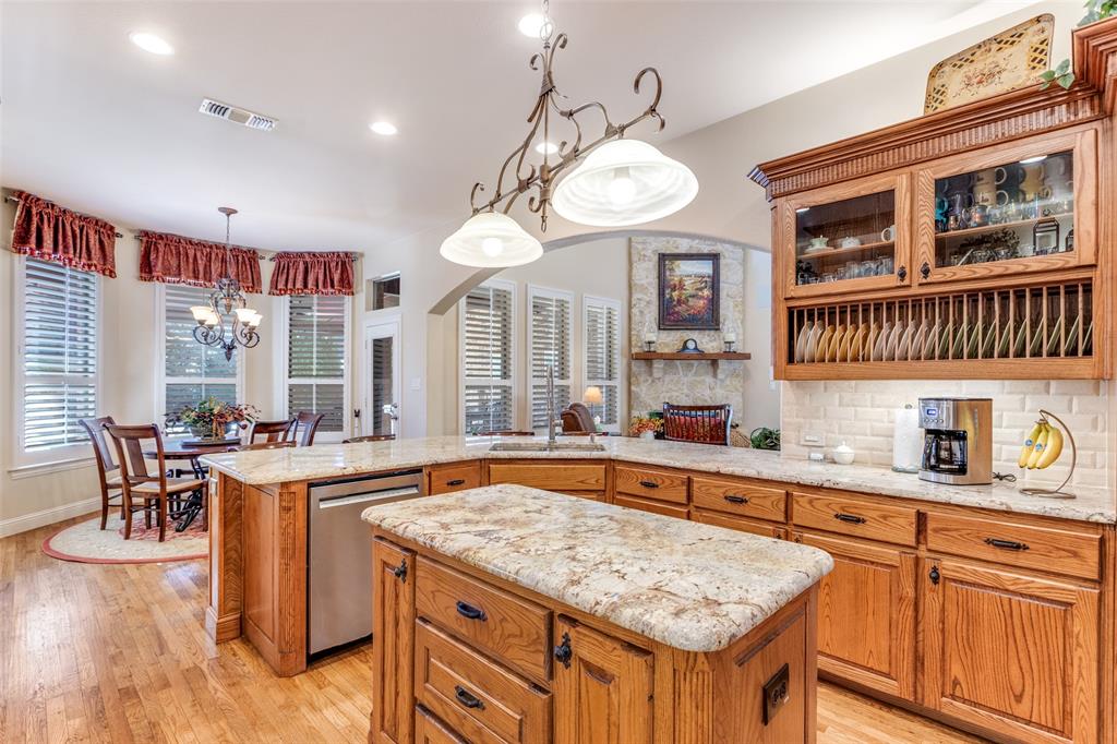 1109 Canton Court Allen, TX 75013 - Photo 11 of 40 a kitchen with stainless steel appliances granite countertop a stove a sink dishwasher a dining table and chairs with wooden floor