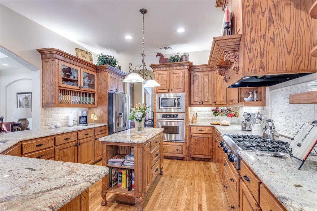 1109 Canton Court Allen, TX 75013 - Photo 9 of 40 a kitchen with a stove a sink and a wooden cabinets