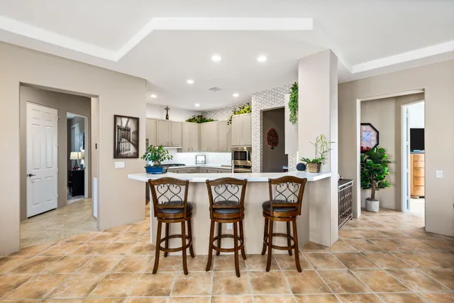 a kitchen with stainless steel appliances kitchen island granite countertop a refrigerator a stove a dining table and chairs