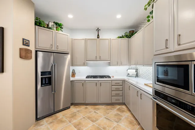 a kitchen with granite countertop a refrigerator oven a sink and white cabinets