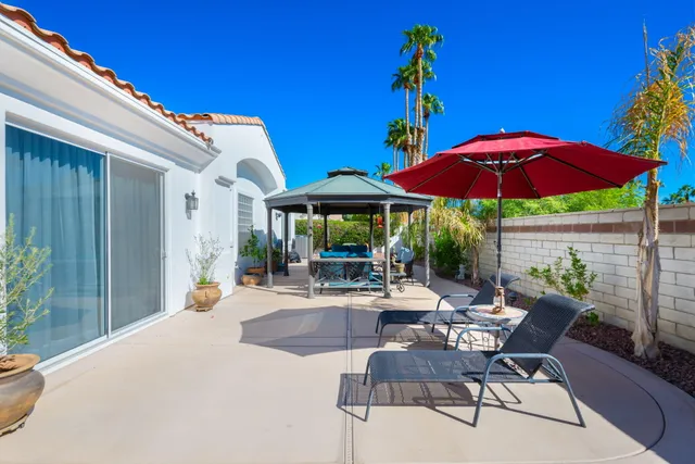 a view of a patio with chairs and table under an umbrella with a fire pit