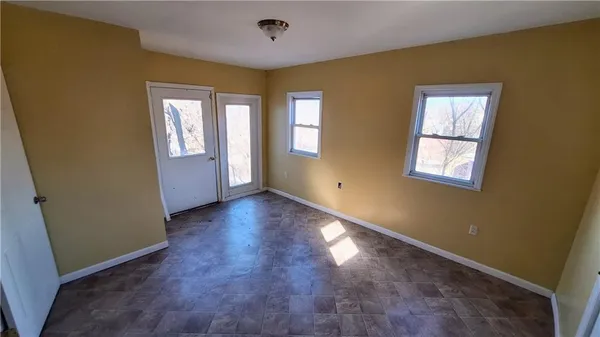 a view of an empty room with window and wooden floor