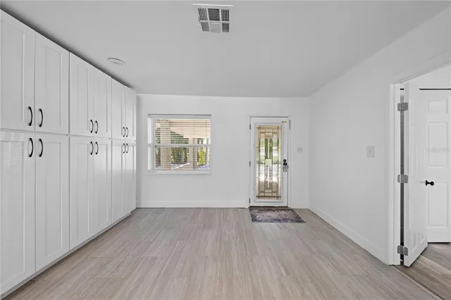 a view of an empty room with wooden floor and a ceiling fan