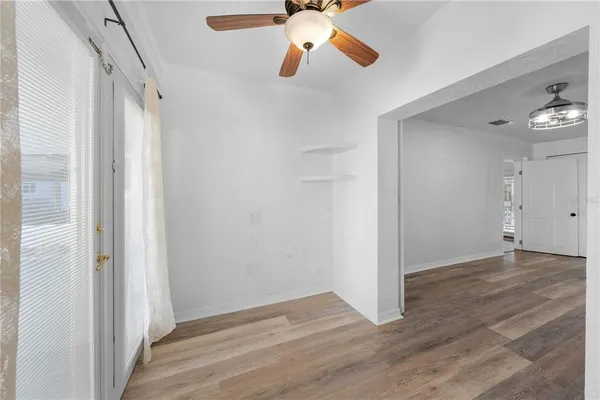 a view of empty room with wooden floor and fan