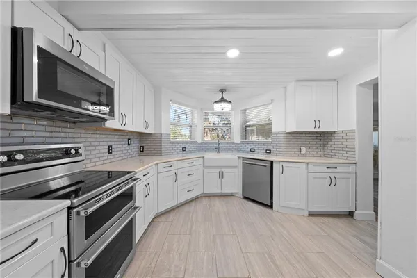 a kitchen with granite countertop white cabinets stainless steel appliances a sink and a window