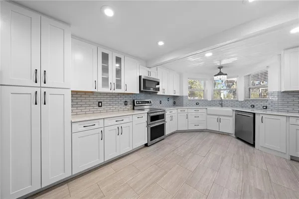 a view of a kitchen with refrigerator and white cabinets