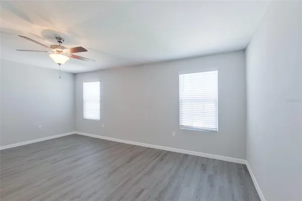 an empty room with wooden floor ceiling fan with window