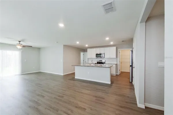 a view of kitchen with kitchen island wooden floor center island and stainless steel appliances