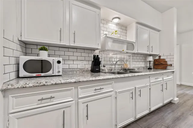 a kitchen with granite countertop white cabinets and a sink