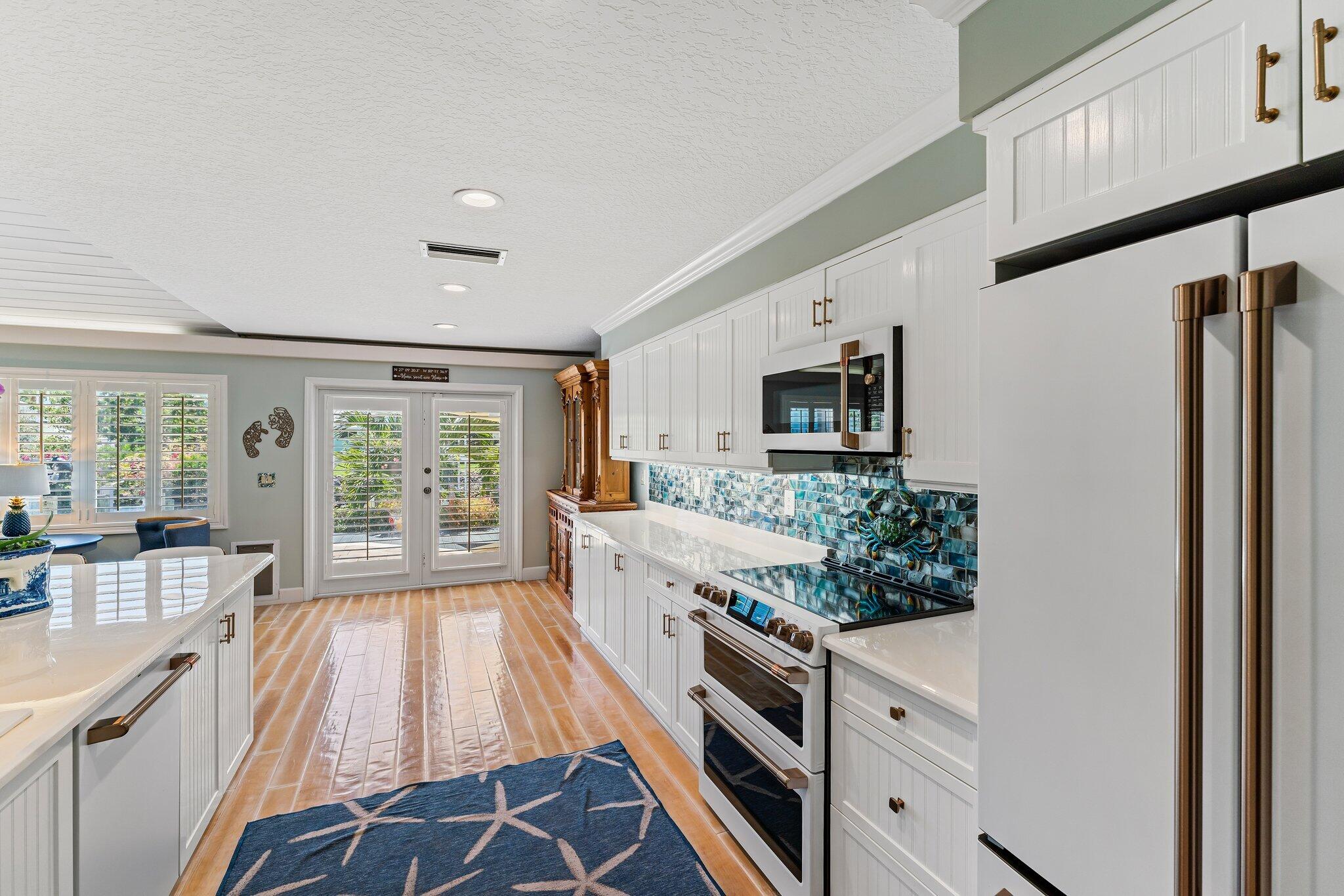 4120 Southeast Whiticar Way Stuart, FL 34997 - Photo 24 of 60 a large white kitchen with stainless steel appliances granite countertop a stove and a large window