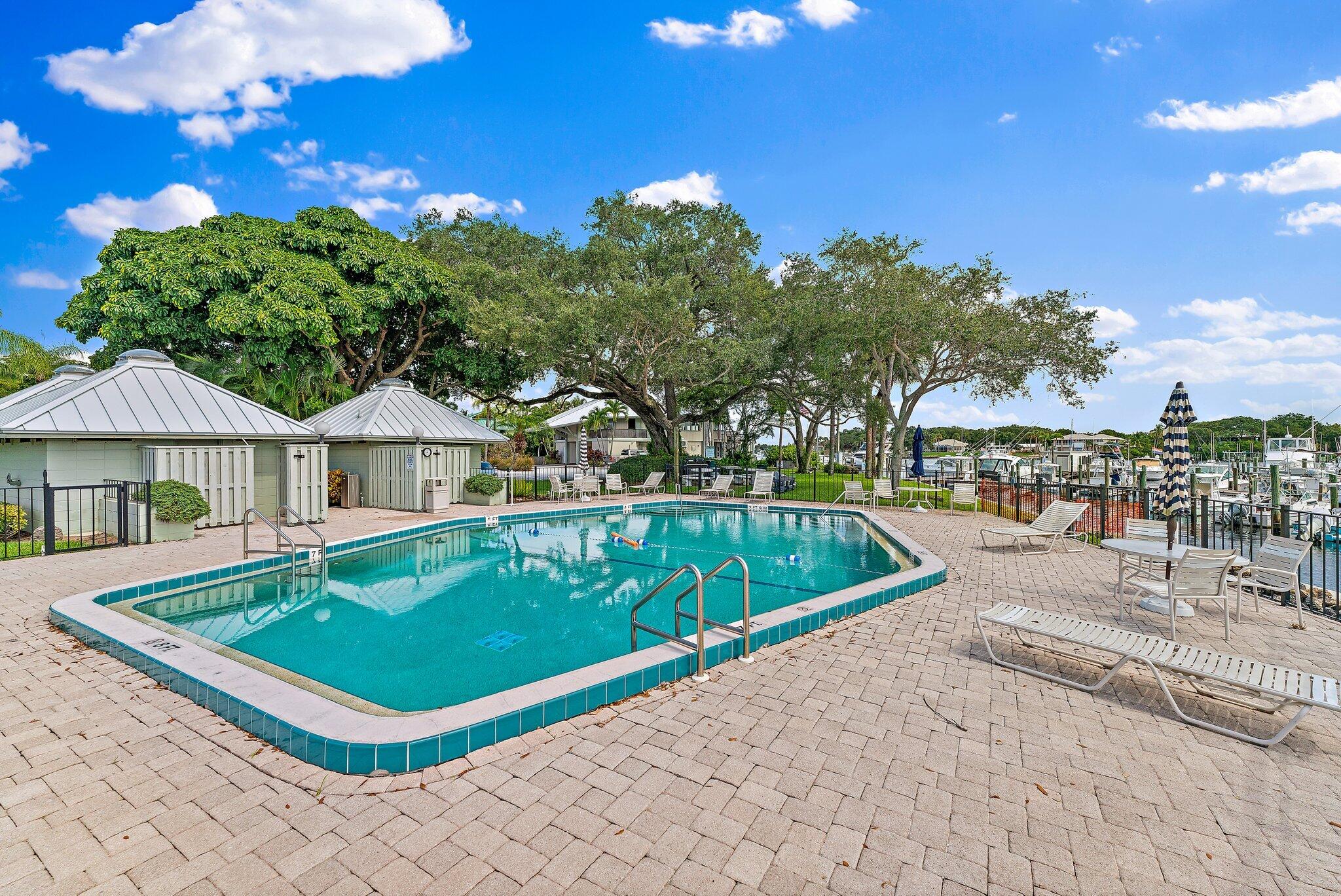 4120 Southeast Whiticar Way Stuart, FL 34997 - Photo 58 of 60 a view of a swimming pool with lawn chairs under an umbrella