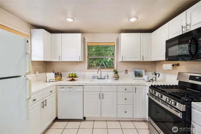 a kitchen with white cabinets sink and appliances