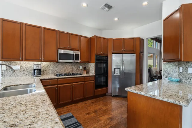 a kitchen with stainless steel appliances granite countertop a refrigerator a sink dishwasher and wooden cabinets with a granite countertops