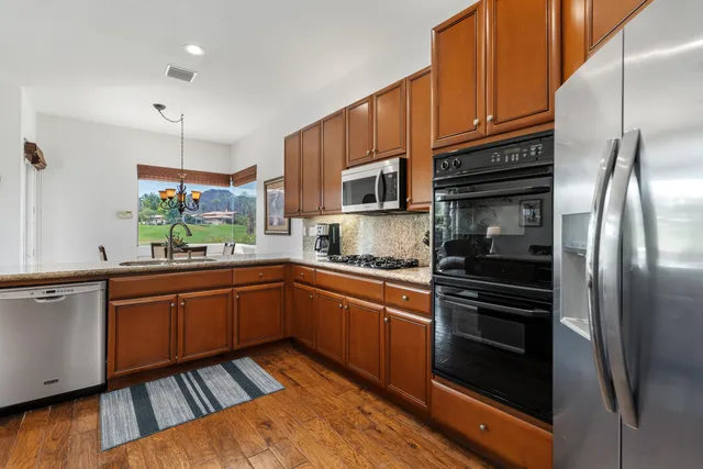 a kitchen with stainless steel appliances granite countertop a refrigerator and a stove top oven