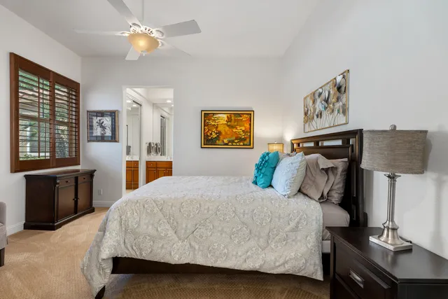 a bedroom with a bed a dresser and potted plants