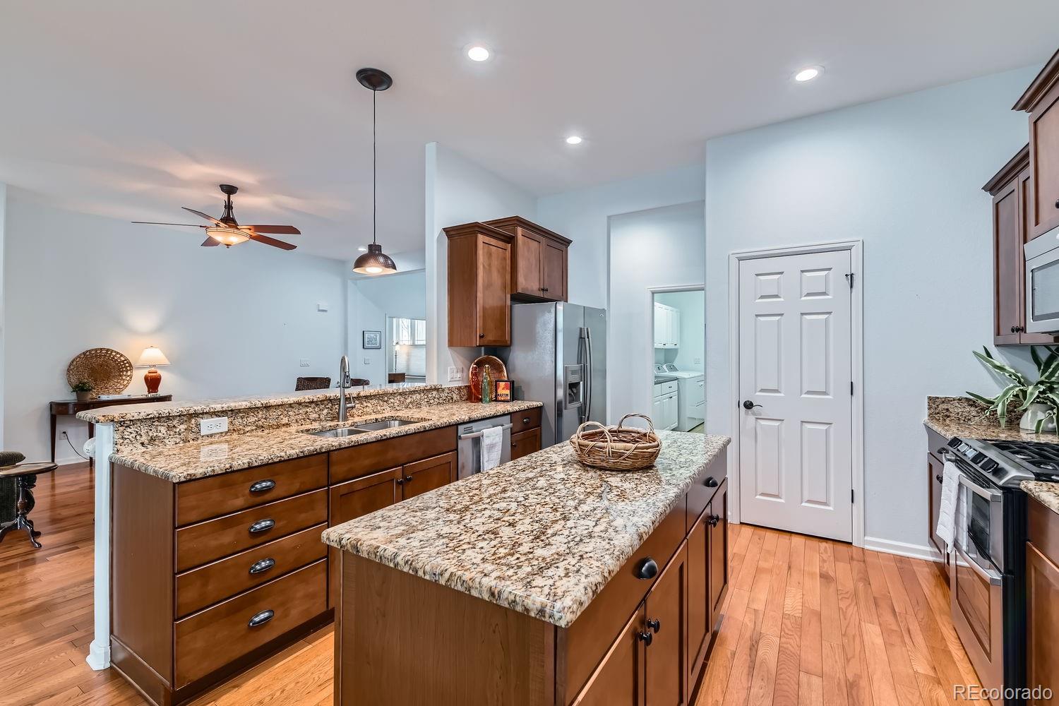 4500 Silver Mountain Loop Broomfield, CO 80023 - Photo 11 of 37 a kitchen with kitchen island granite countertop wooden cabinets and a refrigerator
