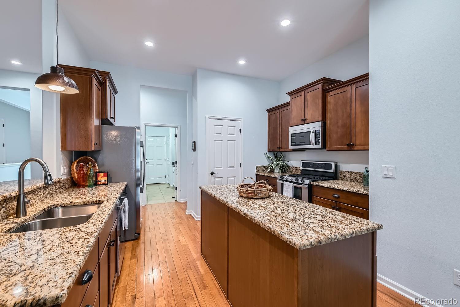 4500 Silver Mountain Loop Broomfield, CO 80023 - Photo 12 of 37 a kitchen with stainless steel appliances granite countertop a sink stove microwave and refrigerator