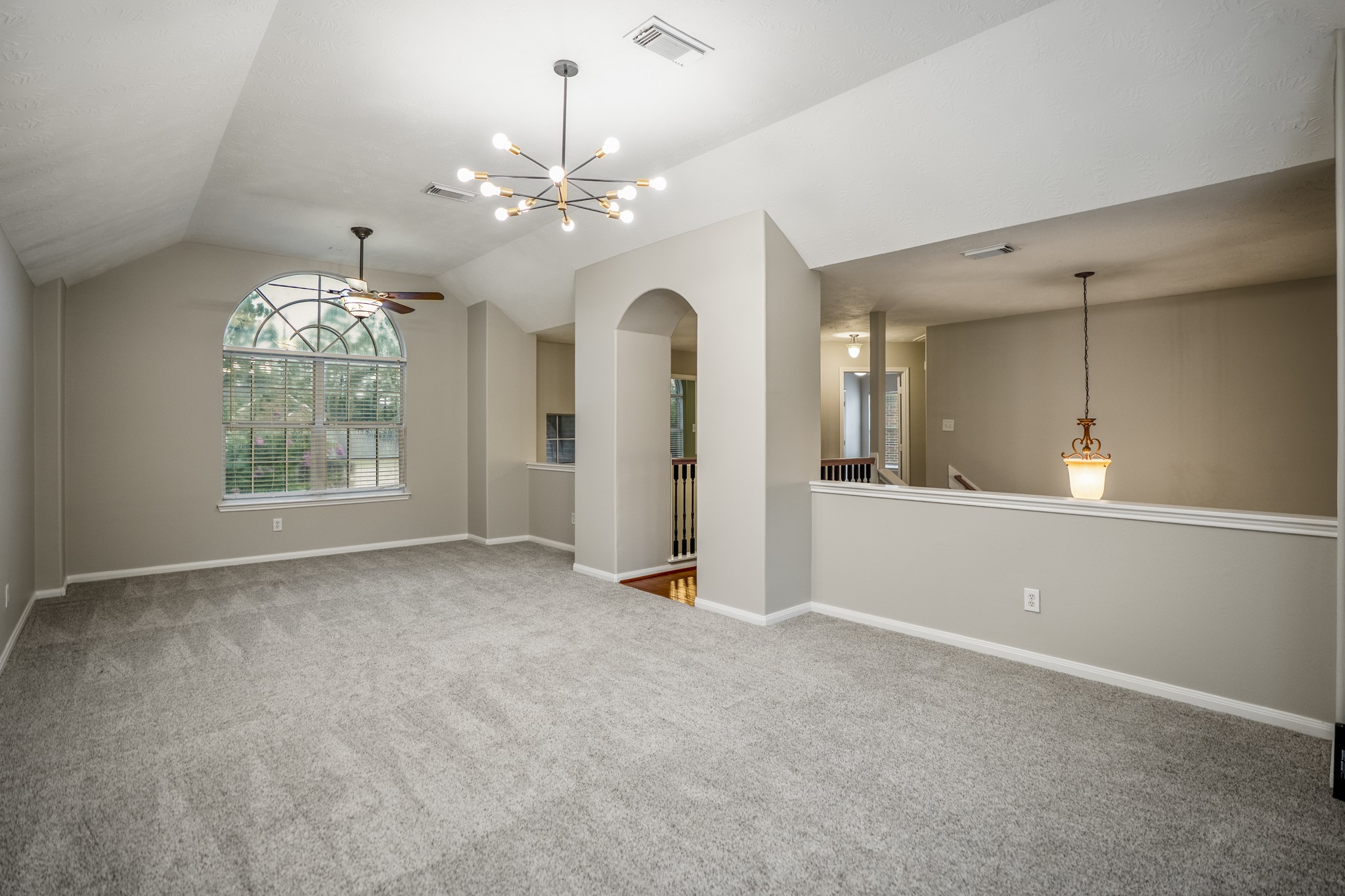 6311 Sparrows Glen Lane Spring, TX 77379 - Photo 24 of 50 At the top of the stairs, the gameroom opens with vaulted ceilings, an arched front window, and an overlook that keeps the second floor visually connected to the entry and living room below.