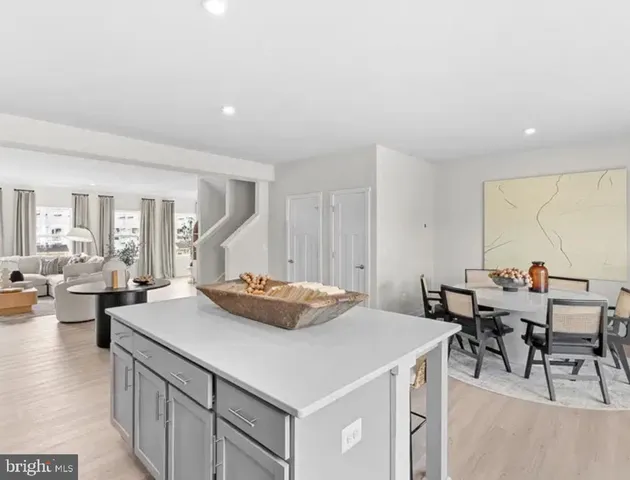 a kitchen with a counter top space a sink a stove and a living room view