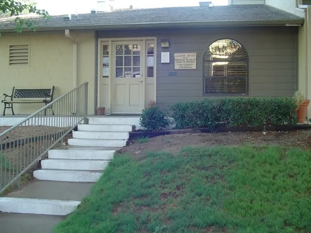 a view of a brick house with a yard and plants