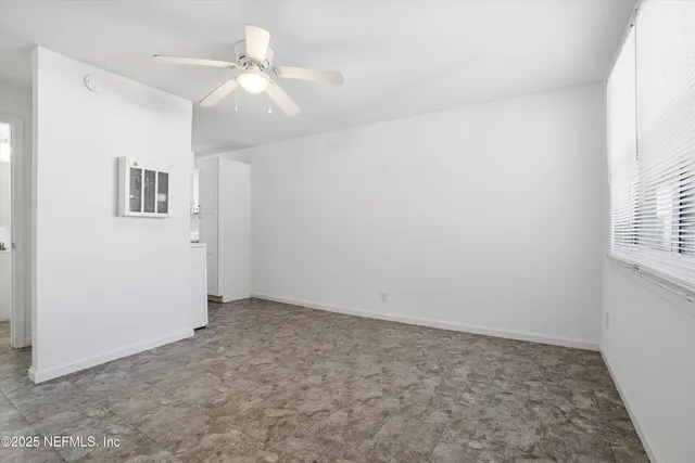 an empty room with windows and chandelier fan