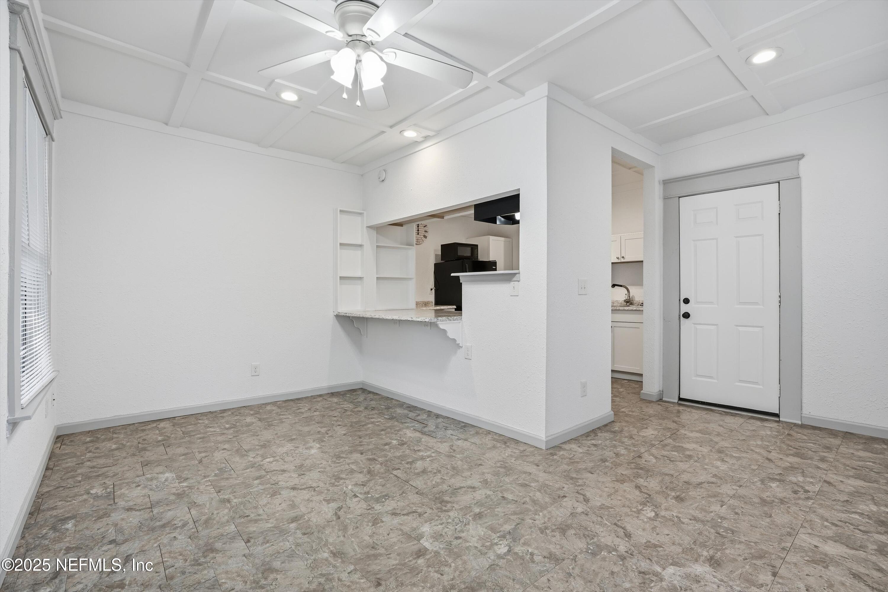 911 Phillips Street Jacksonville, FL 32207 - Photo 8 of 36 an empty room with chandelier fan and kitchen view