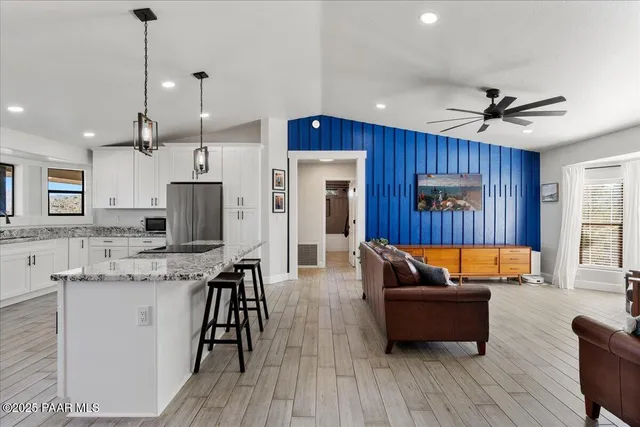 a living room with stainless steel appliances granite countertop furniture wooden floor and a chandelier
