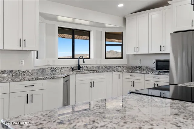 a kitchen with granite countertop a sink stove and cabinets