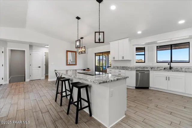 a kitchen with stainless steel appliances kitchen island granite countertop a table chairs sink and cabinets