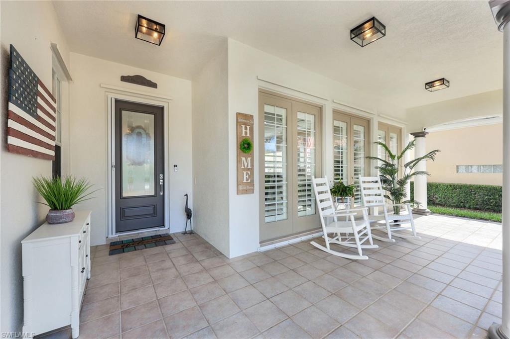 3108 Dominica Way Naples, FL 34119 - Photo 2 of 39 Covered porch with square tile flooring, entry door with decorative glass, and French doors featuring interior plantation shutters.