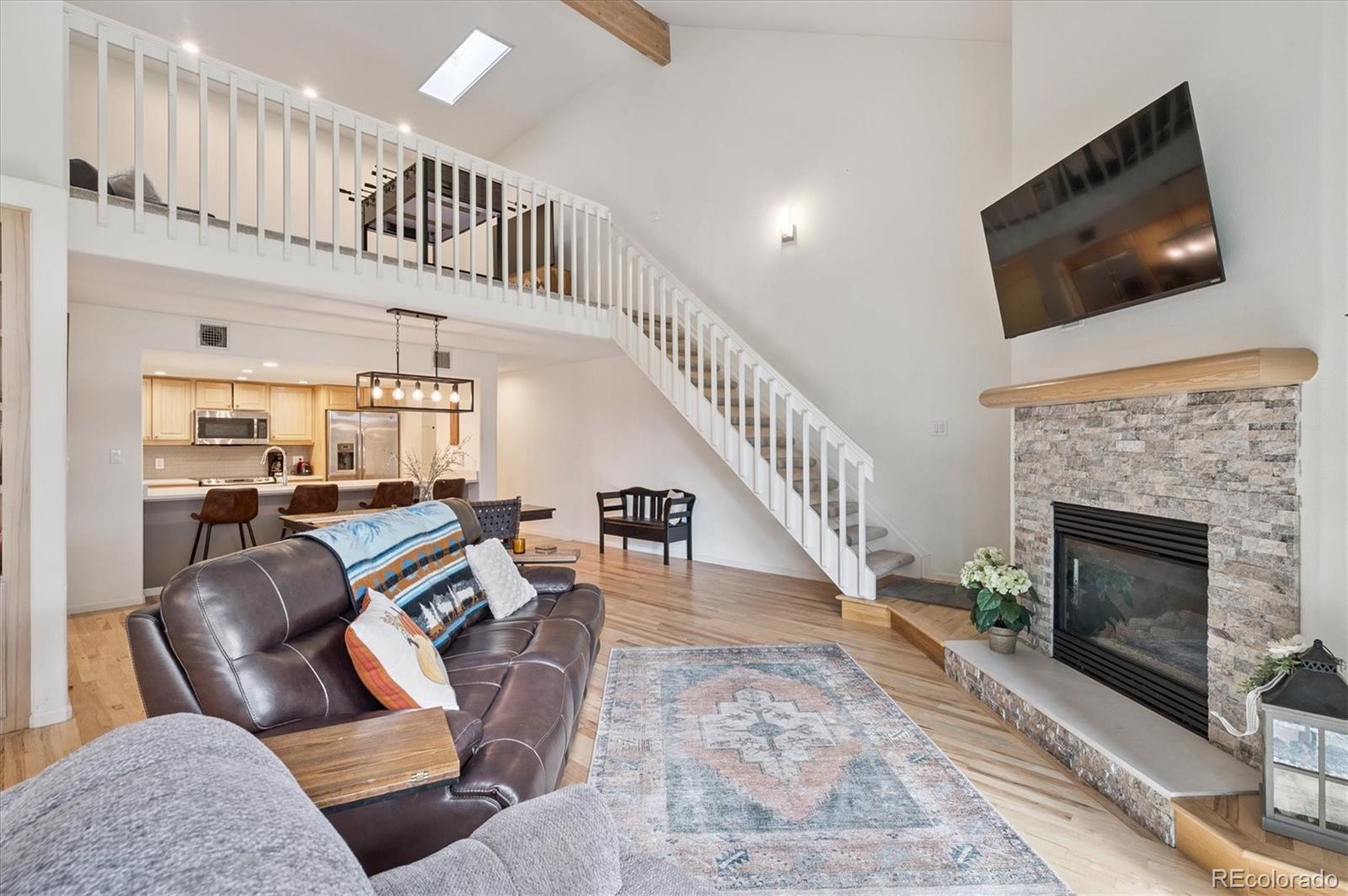 a living room with couches a flat screen tv and a fireplace with wooden floor