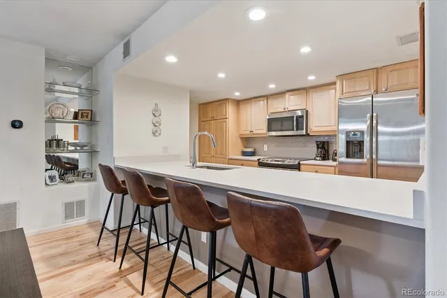 a kitchen with stainless steel appliances granite countertop a stove a sink a refrigerator with a dining table and chairs