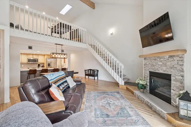 a living room with couches a flat screen tv and a fireplace with wooden floor
