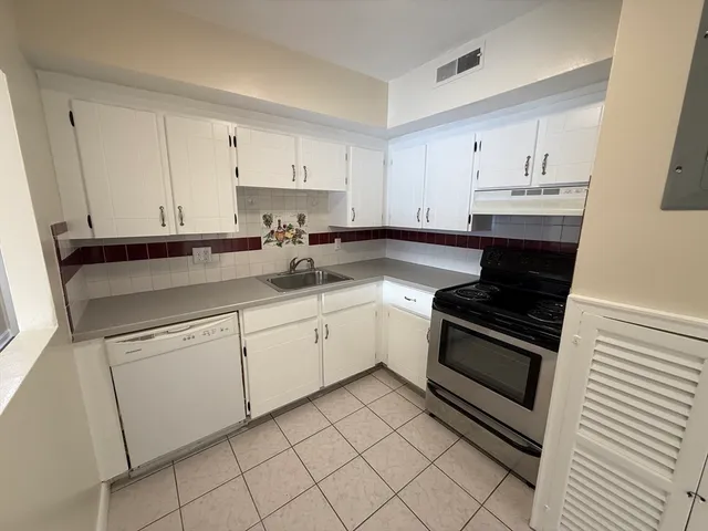 a kitchen with granite countertop white cabinets and white appliances