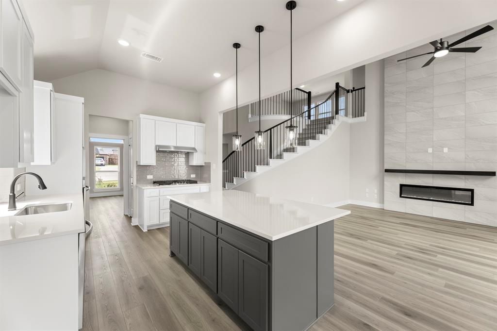 941 Gold Finch Lane Forney, TX 75126 - Photo 11 of 27 a open kitchen with kitchen island a sink and a stove with wooden floor
