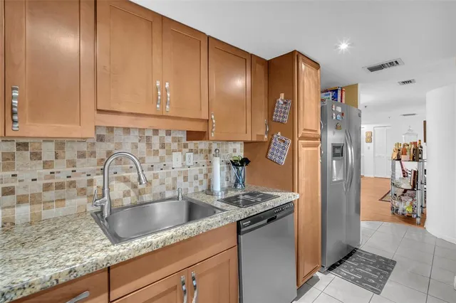 a kitchen with stainless steel appliances granite countertop a sink a refrigerator and cabinets