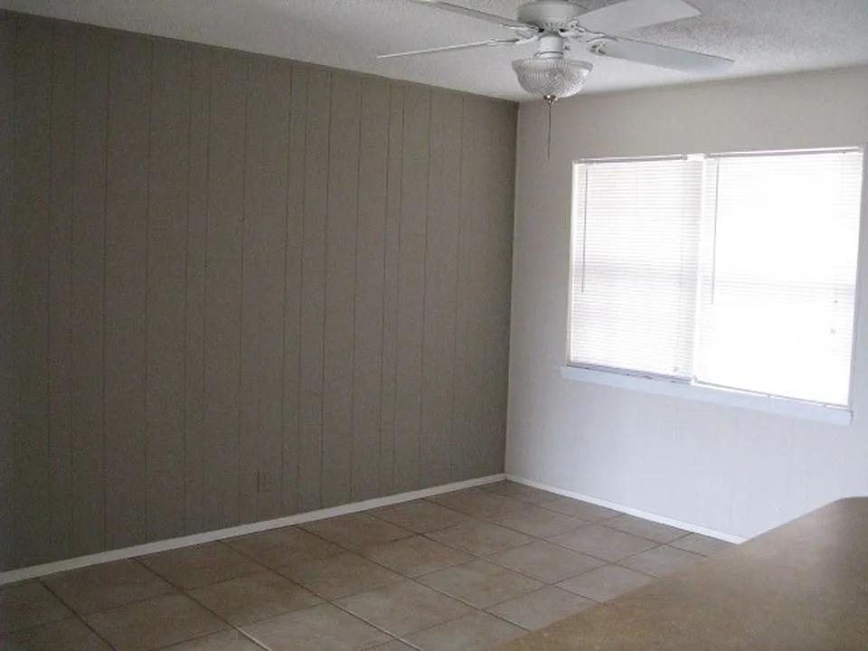 4004 Vicky Street Big Spring, TX 79720 - Photo 7 of 13 Room featuring a paneled accent wall, tiled flooring, and a ceiling fan with integrated lighting
