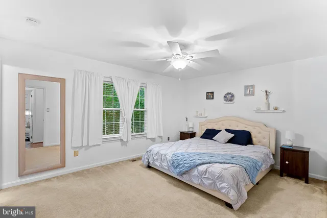 a bedroom with a large bed and a chandelier fan