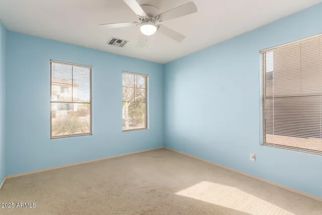 an empty room with windows and fan