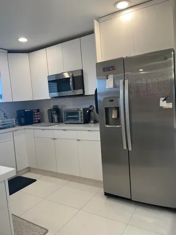 a kitchen with stainless steel appliances granite countertop a refrigerator a sink and white cabinets