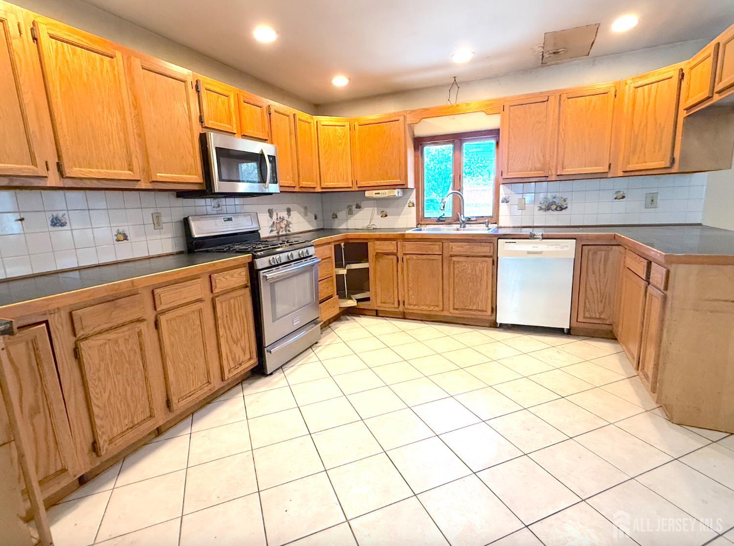 4 Forrestal Road Kendall Park, NJ 08824 - Photo 11 of 22 a kitchen with stainless steel appliances granite countertop a stove top oven a sink a dining table and chairs