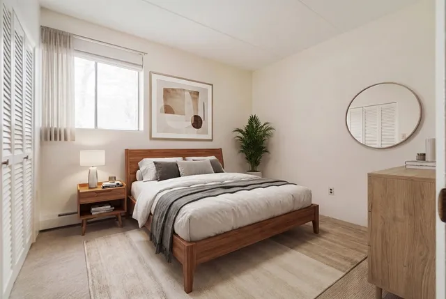 a spacious bedroom with a bed a mirror and a window