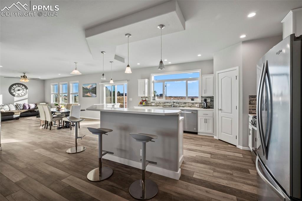 9393 North Log Road Calhan, CO 80808 - Photo 9 of 49 a kitchen with kitchen island granite countertop wooden floors refrigerator and cabinets