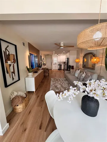 a living room with furniture a rug kitchen view and a chandelier