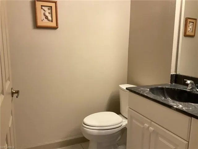 a bathroom with a granite countertop toilet and a sink