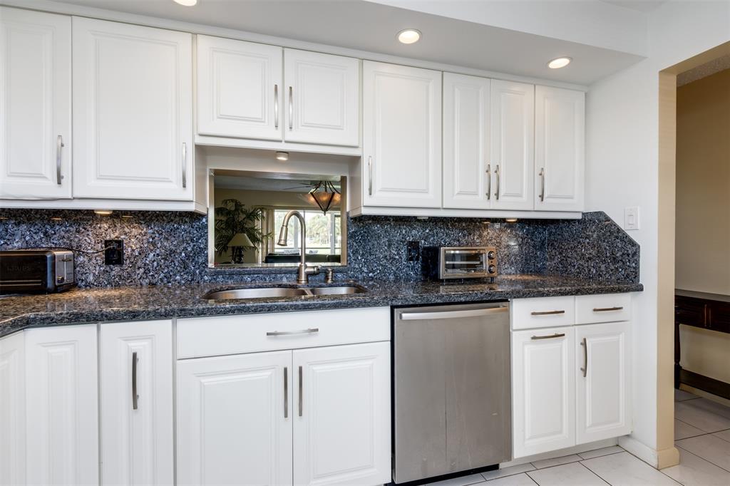 190 Southeast 5th Avenue, Unit 108 Dania Beach, FL 33004 - Photo 3 of 40 a kitchen with granite countertop white cabinets and a stainless steel appliances