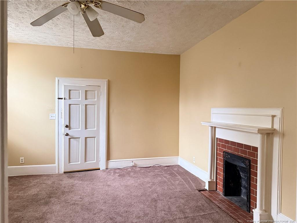 1201 Clark Street Fayetteville, NC 28305 - Photo 3 of 9 a view of an empty room with chandelier fan and fire place