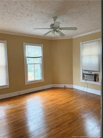 a view of an empty room with a window and wooden floor