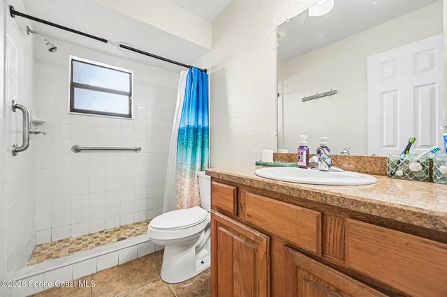 a bathroom with a granite countertop sink a toilet and shower