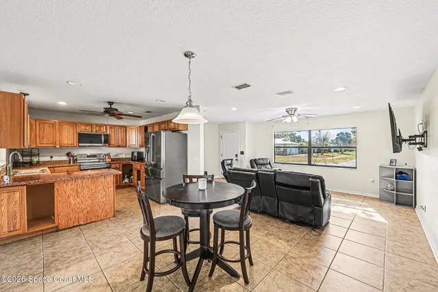 a open kitchen with stainless steel appliances kitchen island granite countertop a table and chairs in it